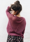 Model wearing knitted sweater with dramatic sweeping triangle of mesh lace across the back.
