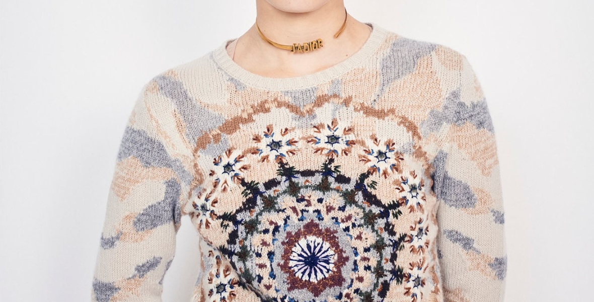 Model wearing Dior summer 2019 collection, including sweater in soft peach, blue and navy colours forming an abstract, kaleidoscope design in intarsia colour-work with embroidery details.
