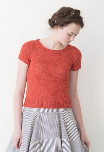 Woman wearing fitted, orange top knitted in linen and with classic crew neck and ribbed border at hem.
