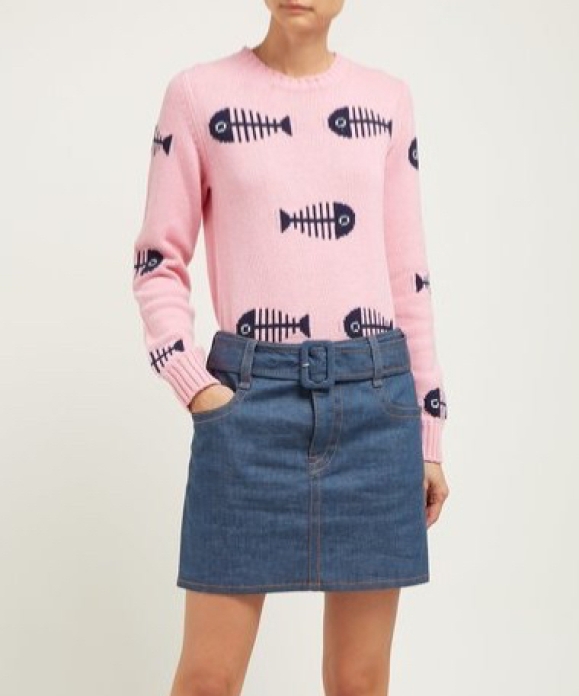 Woman wearing knitted pink jumper with repeated intarsia motif of a fish skeleton in navy.