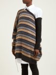 Woman wearing oversized, knitting sweater in stripes of grey, orange and dark brown with stranded colourwork cross design, with one dark brown sleeve, giant cut outs and slouchy fit.