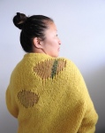 Woman wearing bright yellow, knitted sweater with faux, ripped holes made out of lighter weight yarn.
