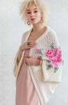 Model wearing oversized, knitted mesh cardigan with large cross-stitch embroidered roses.