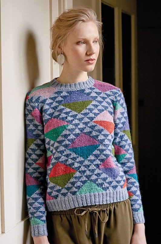 Woman wearing knitted jumper with all-over, triangle intarsia design in many colours.