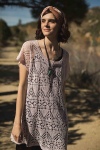 Model wearing tunic length, knitted linen top with all-over lace design, in soft pink.