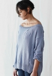 Woman wearing pale blue, knitted sweater with faux rips made of dropped stitches.