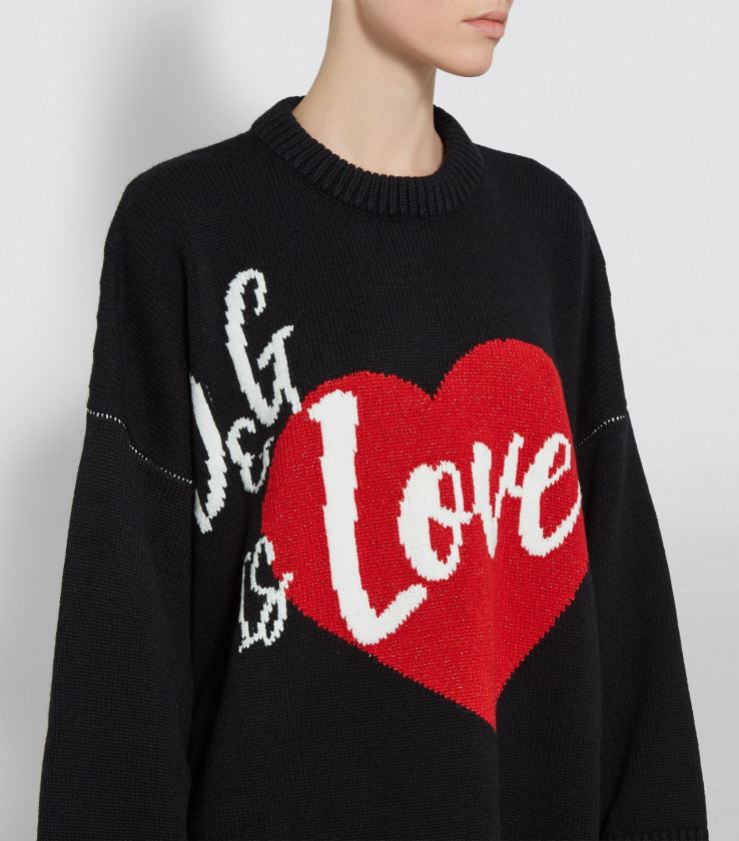Model wearing knitted, black sweater with ‘D&G is love’ slogan formed in intarsia colour-work in white and red.