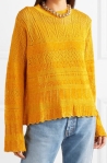 Model wearing yellow sweater with all-over lace panel details and flared sleeves. From McQ Alexander McQueen.