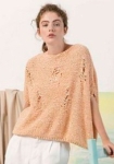 Woman wearing chunky, cotton knitted sweater in pale orange, with distressed effect created by faux holes and rips formed by lace stitches.