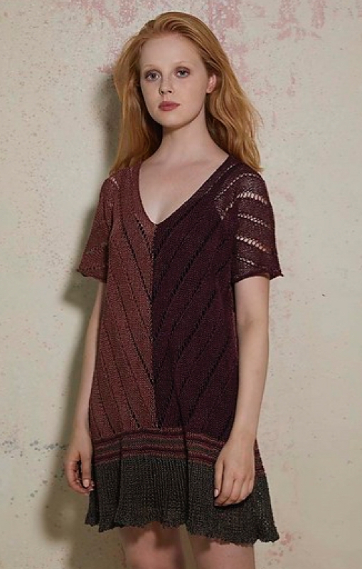 Woman wearing short, knitted dress with deep v-neck, short sleeves and with lace and intarsia colour blocking in brown shades.