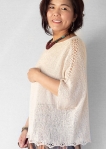 Woman wearing oversized, cream, cotton sweater with dolman sleeves and eyelet lace detail at shoulders.