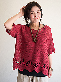 Woman wearing knitted, linen top with zigzag lace detail at hem.
