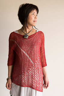Woman wearing knitted, red sweater made from tencel fibre, with asymmetric hem and lace panel.