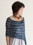 Woman wearing grey blue, knitted, silk/cotton poncho in all-over dropped stitch cable.