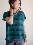 Woman wearing short sleeved top knitted in cotton, with contrasting strips of teal and blue.