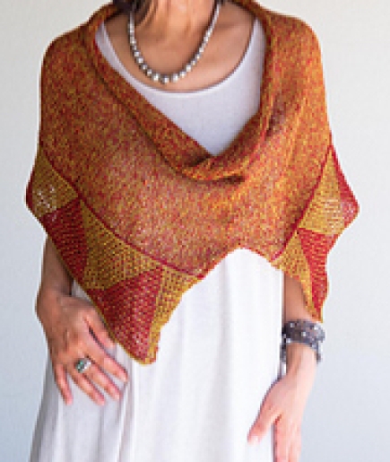 Woman wearing knitted cotton, burnt orange poncho or cowl with mosaic stitch triangle border in contrasting yellow.